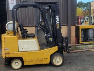 YALE GLC040 Yellow Yale forklift parked outside a building with storage containers in the background.