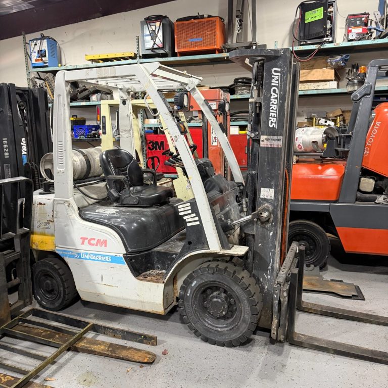 Monthly Forklift Rental Photo A white and black forklift parked in a warehouse with other forklifts visible in the background.
