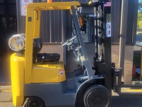 TCM FCG15F9 Yellow forklift positioned outdoors beside a building.